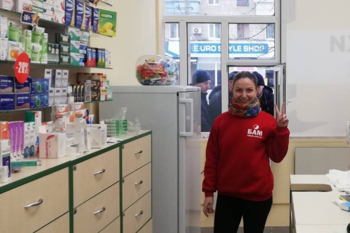 Una farmacéutica de Ucrania, con pacientes esperando a ser atendidos por el torno. Foto: PODOROZHNYK PHARMACY NETWORK